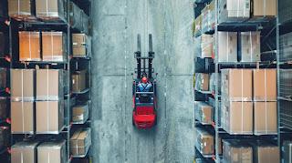 A forklift operator working with automated equipment in a modern warehouse. A forklift operator working with automated equipment in a modern warehouse.