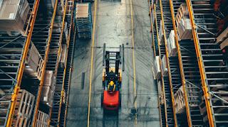 A forklift operator working with automated equipment in a modern warehouse. A forklift operator working with automated equipment in a modern warehouse.